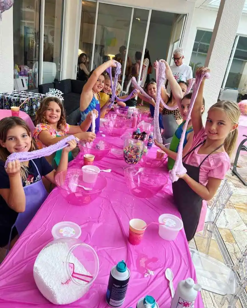 A group of girls at a table with pink tablecloths enjoying a Mobile Slime Party.